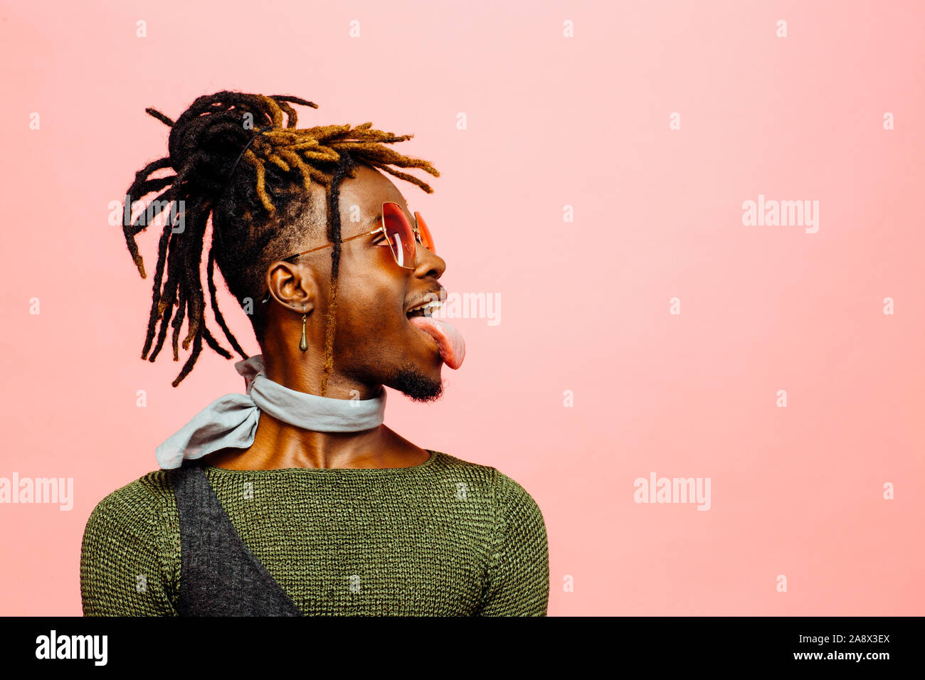 Studio profile portrait of trendy young man with sunglasses and  tongue out Stock Photo