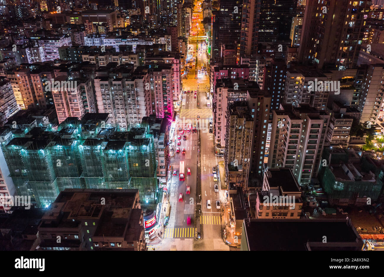 Car, taxi, and bus traffic on road intersection at night in Hong Kong downtown district, drone aerial top view. Street commuter Asia city life concept Stock Photo