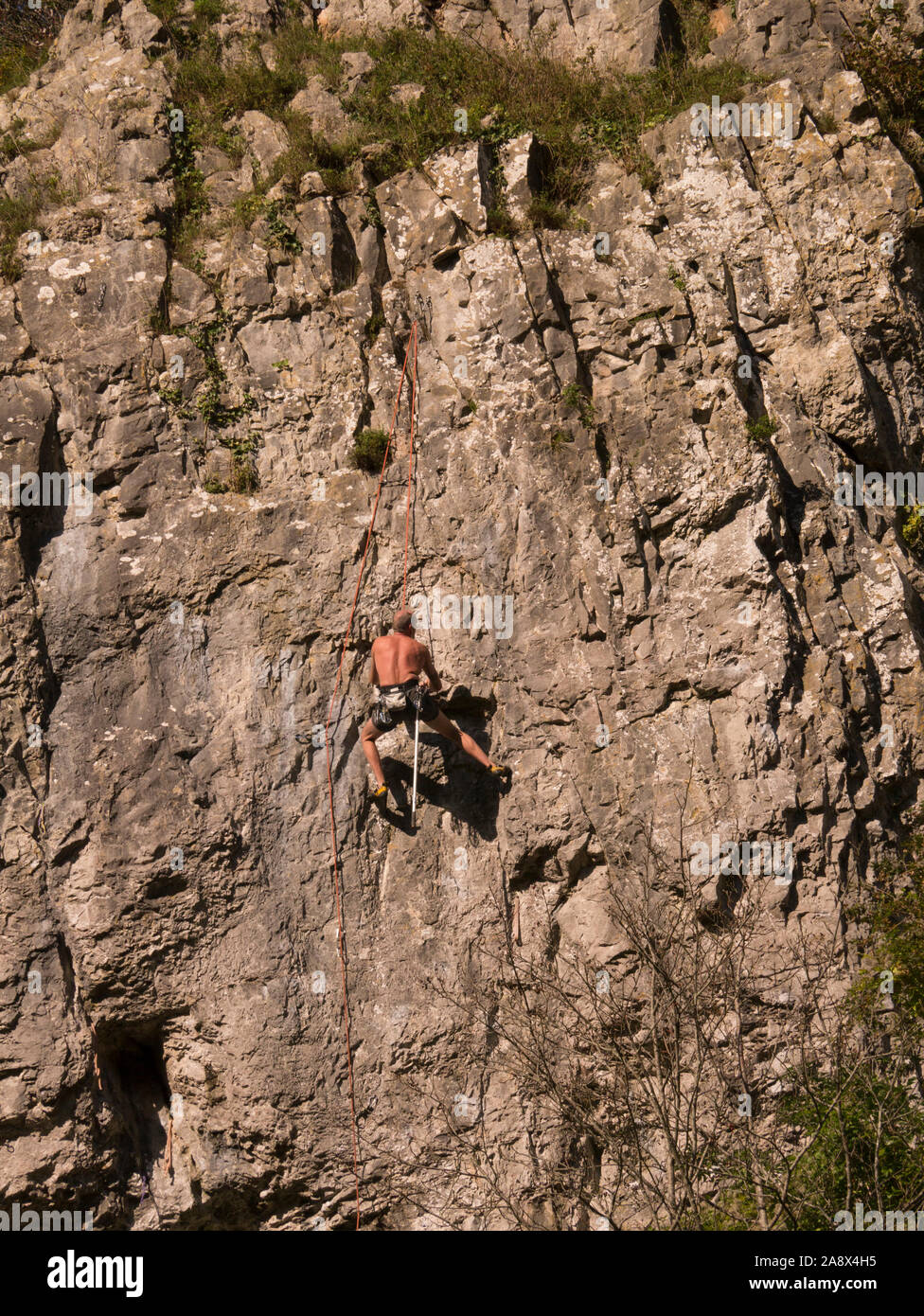 Bare chested man climbing limestone rock of Cheddar in Mendip