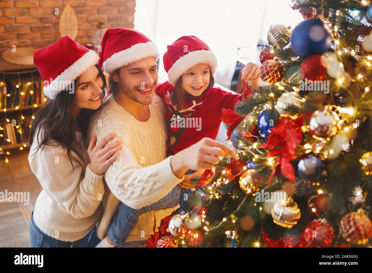 Happy family decorating Christmas tree with bubbles in living room Stock Photo