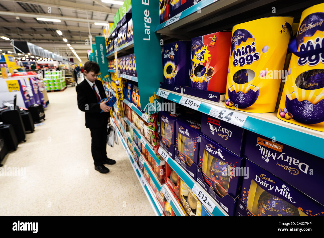 A young handsome school boy with ADHD, Autism, Aspergers syndrome looks, browses, looks at some Easter eggs in the local Tesco extra supermarket store Stock Photo
