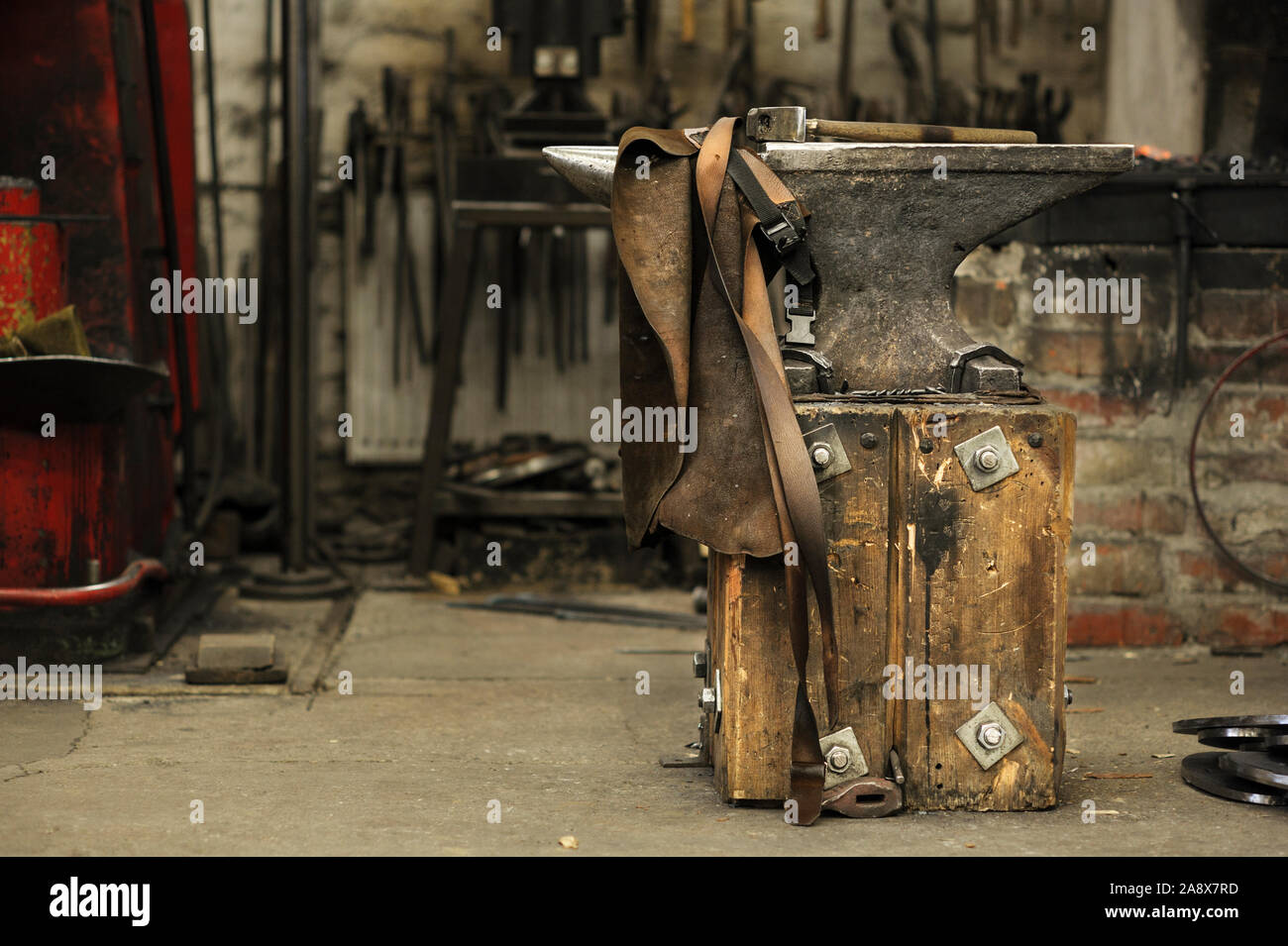 Anvil, hammer and leather apron in smithy Stock Photo