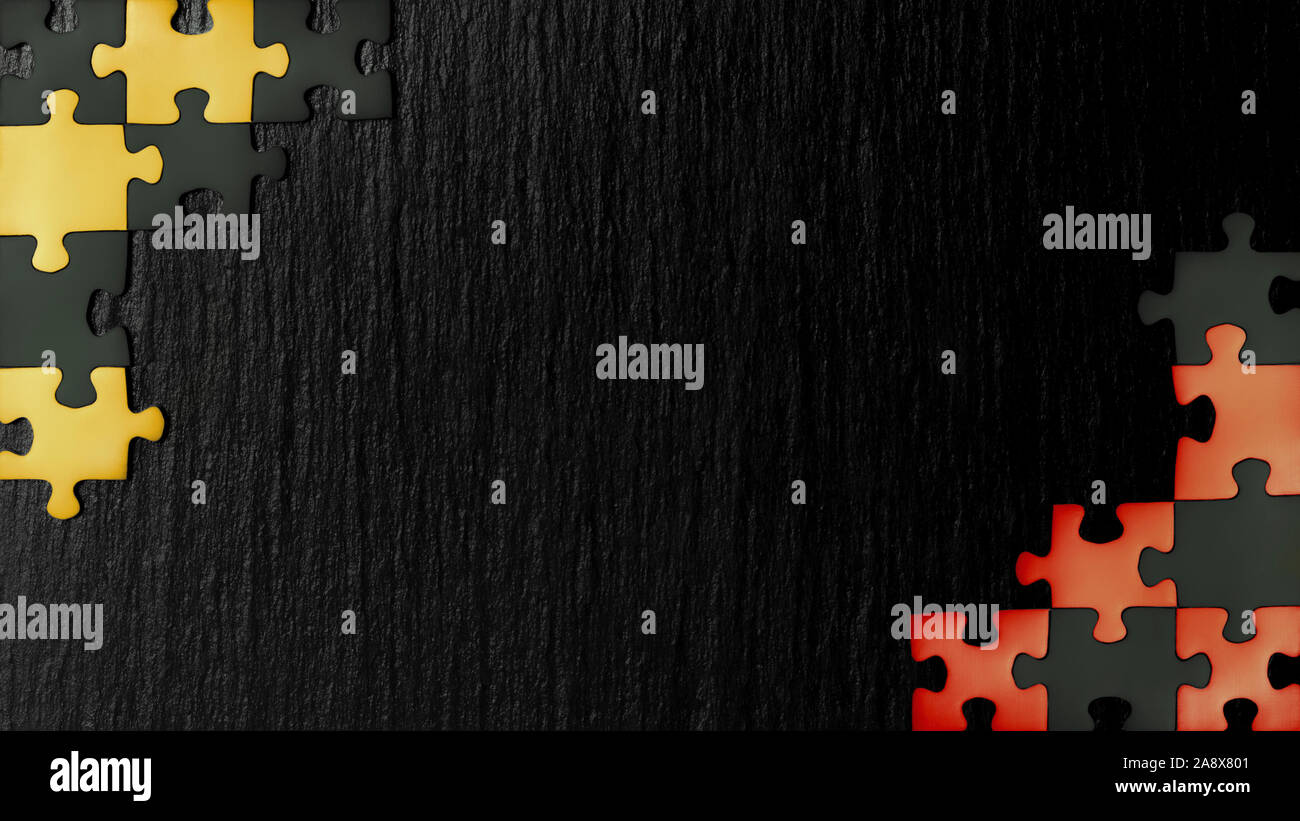 Red, yellow and black puzzles in the corners on a black slate stone background. Colors found on the flags of Belgium, Germany and Uganda. A frame with Stock Photo