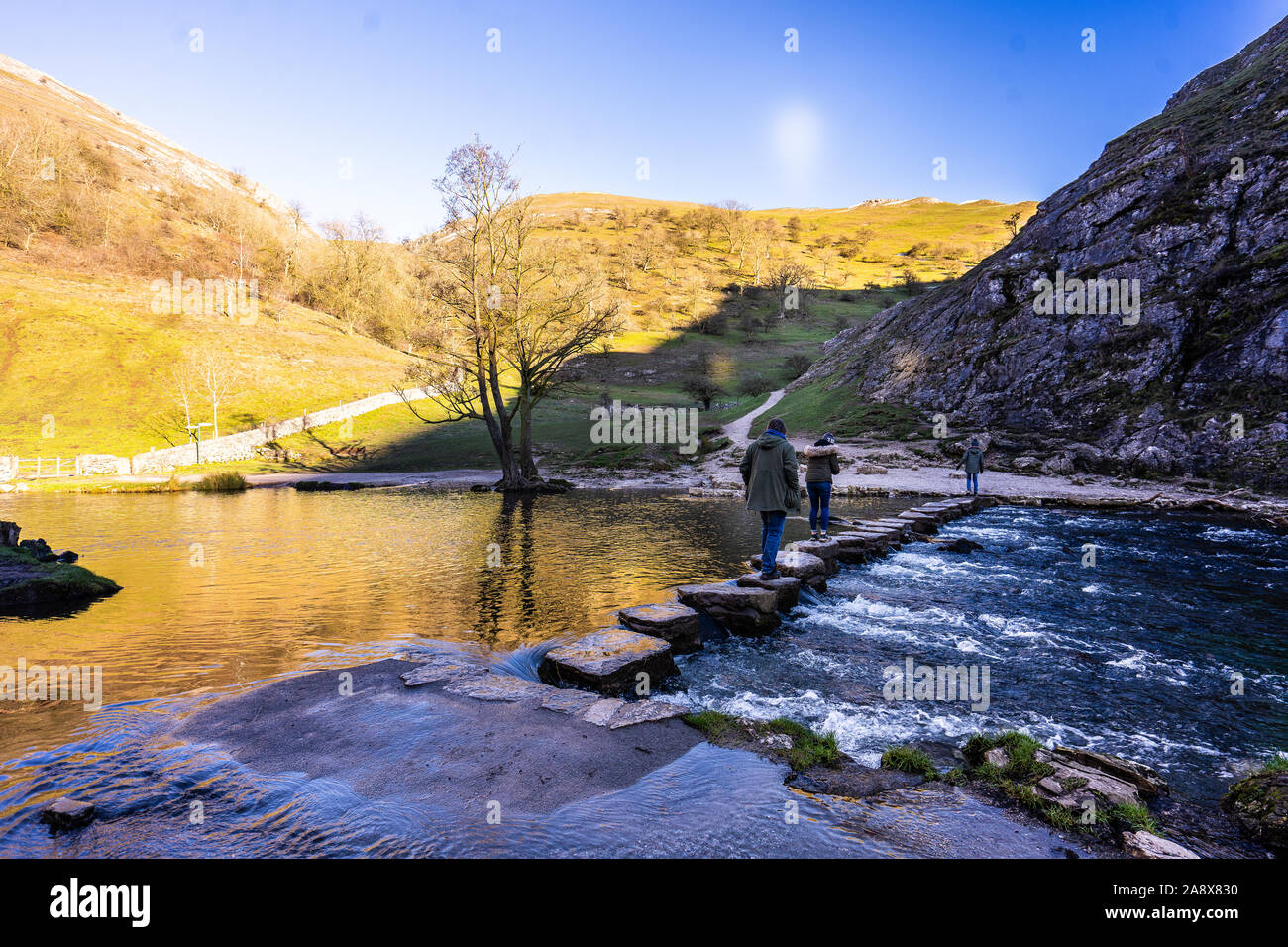People enjoy a day out at the famous Dovedale stepping stones in the Derbyshire Peak District National Park, part of the National trust Stock Photo