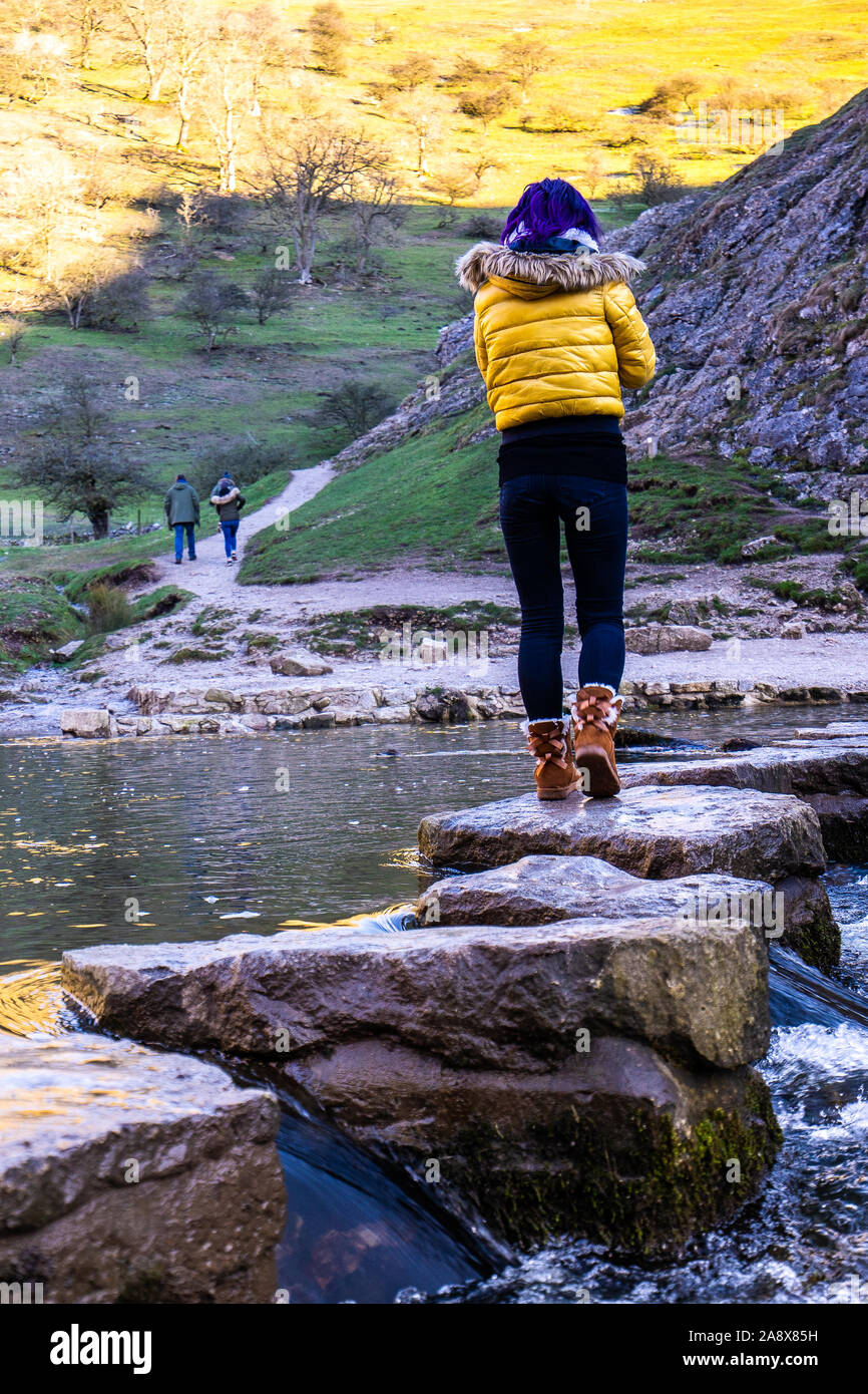 A pretty young athletic women crosses over the famous Dovedale stepping ...