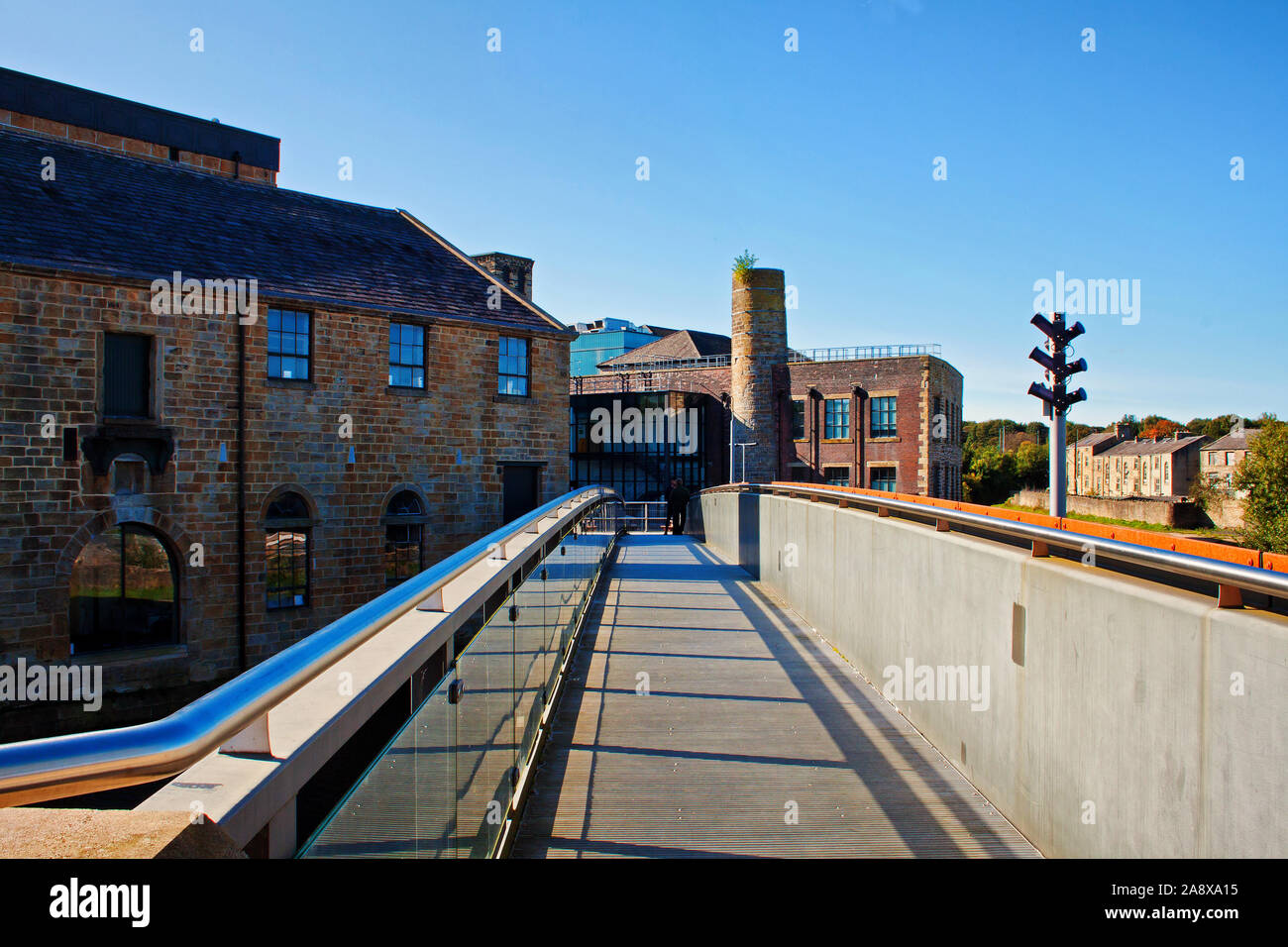 The new footbridge at Weavers Triangle, Burnley. With distant figures below the lowered chimney at the focal point of the pictiure Stock Photo