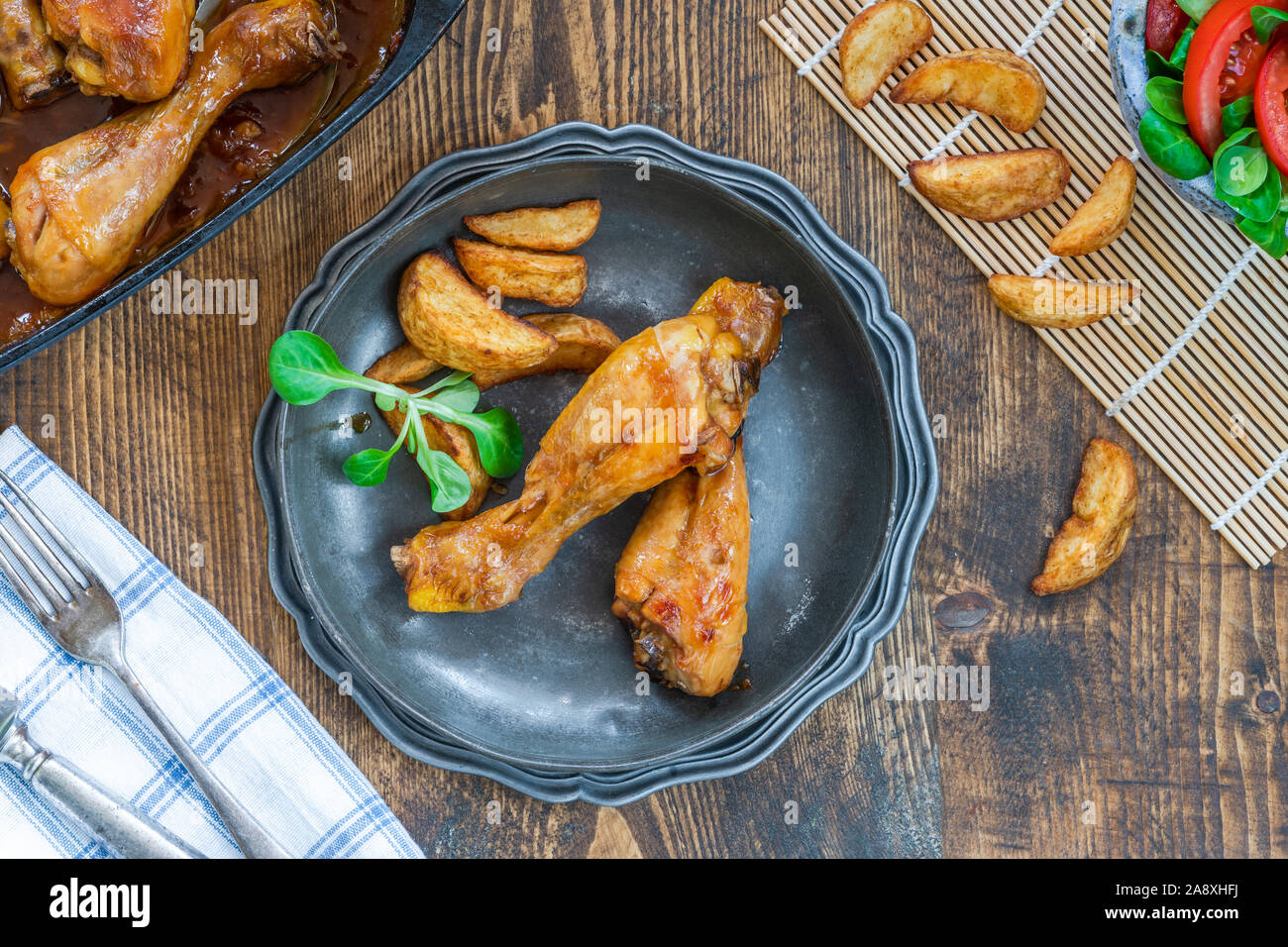 Chicken drumsticks in ginger beer sauce with potato wedges and salad - overhead view Stock Photo
