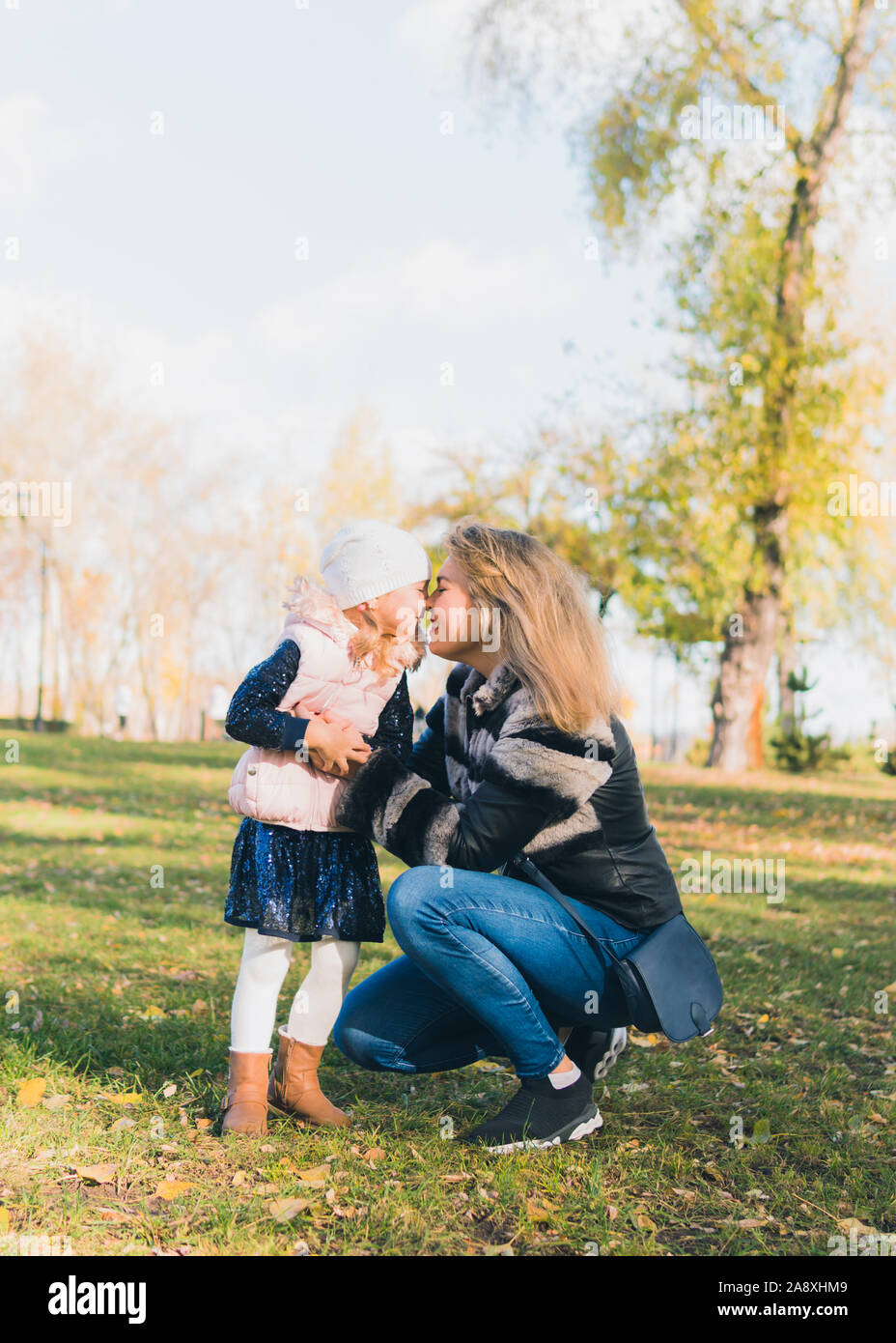 Happy mother and her daughter spending time in the autumn city park ...