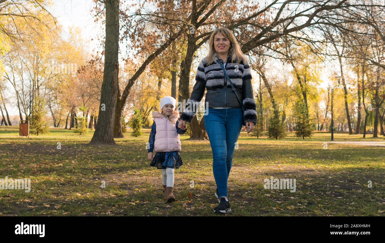 Happy mother and her daughter spending time in the autumn city park ...