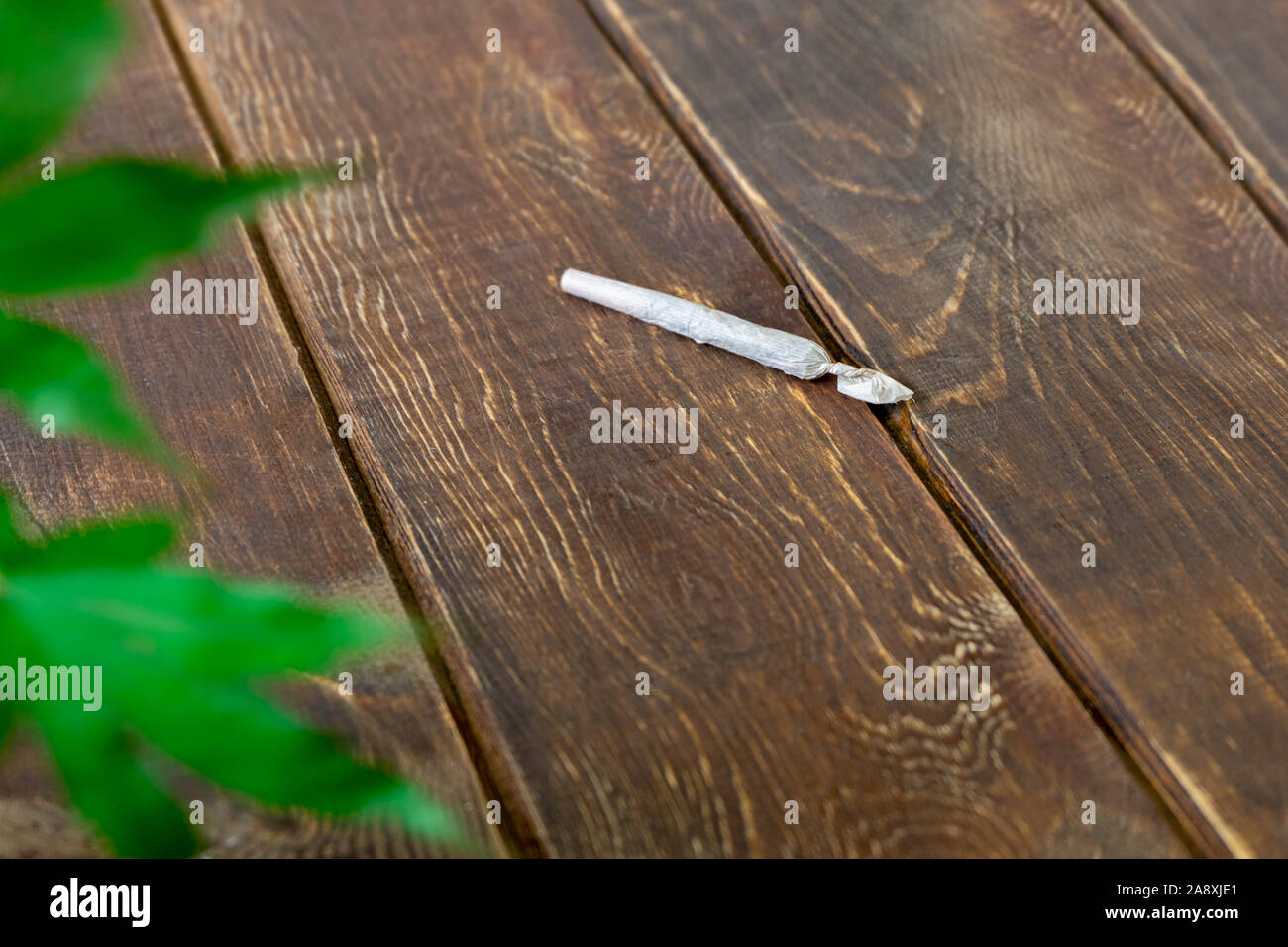Rolled canabis (marijuana) joint on wooden table Stock Photo