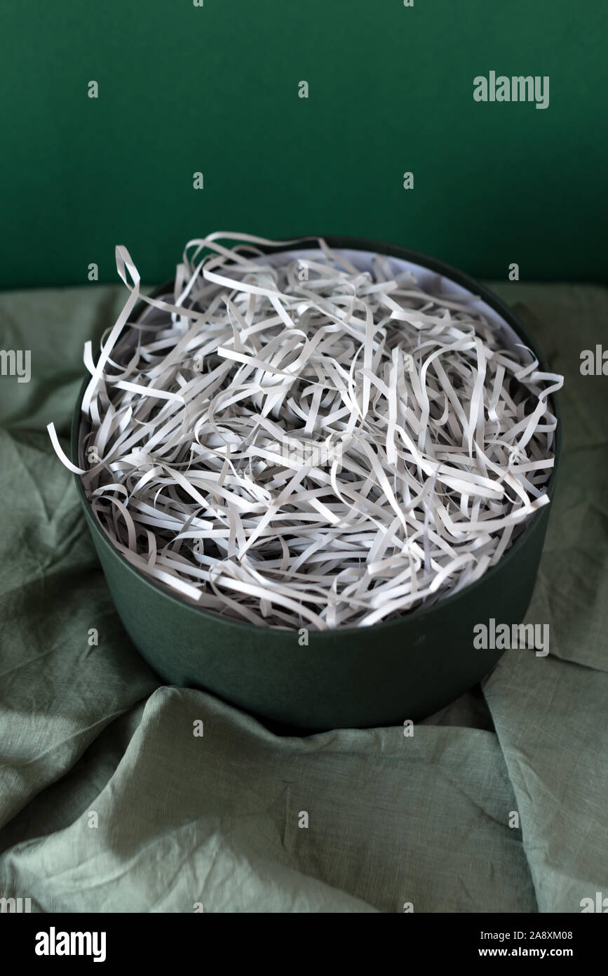 Opened gift box with decorative straw, filler, shavings, paper ribbons