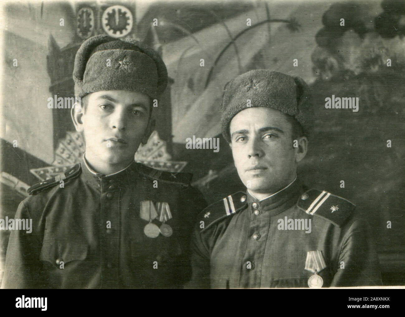 1947 year. Two fellow soldiers of the Red Army in tunics and caps with earflaps. On the chest of the fighters - battle medals 'For Victory over Japan.' THE USSR. Stock Photo