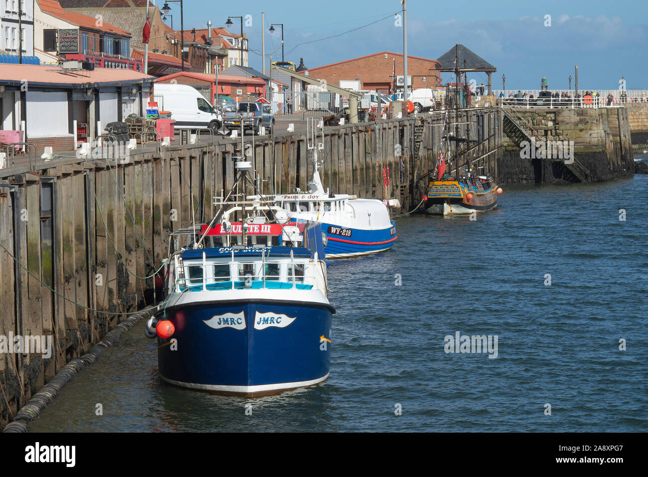 Fishing Boats and a Pirate Ship Tourist Boat Tied Up to the Whitby Quayside on the River Esk North Yorkshire England United Kingdom UK Stock Photo
