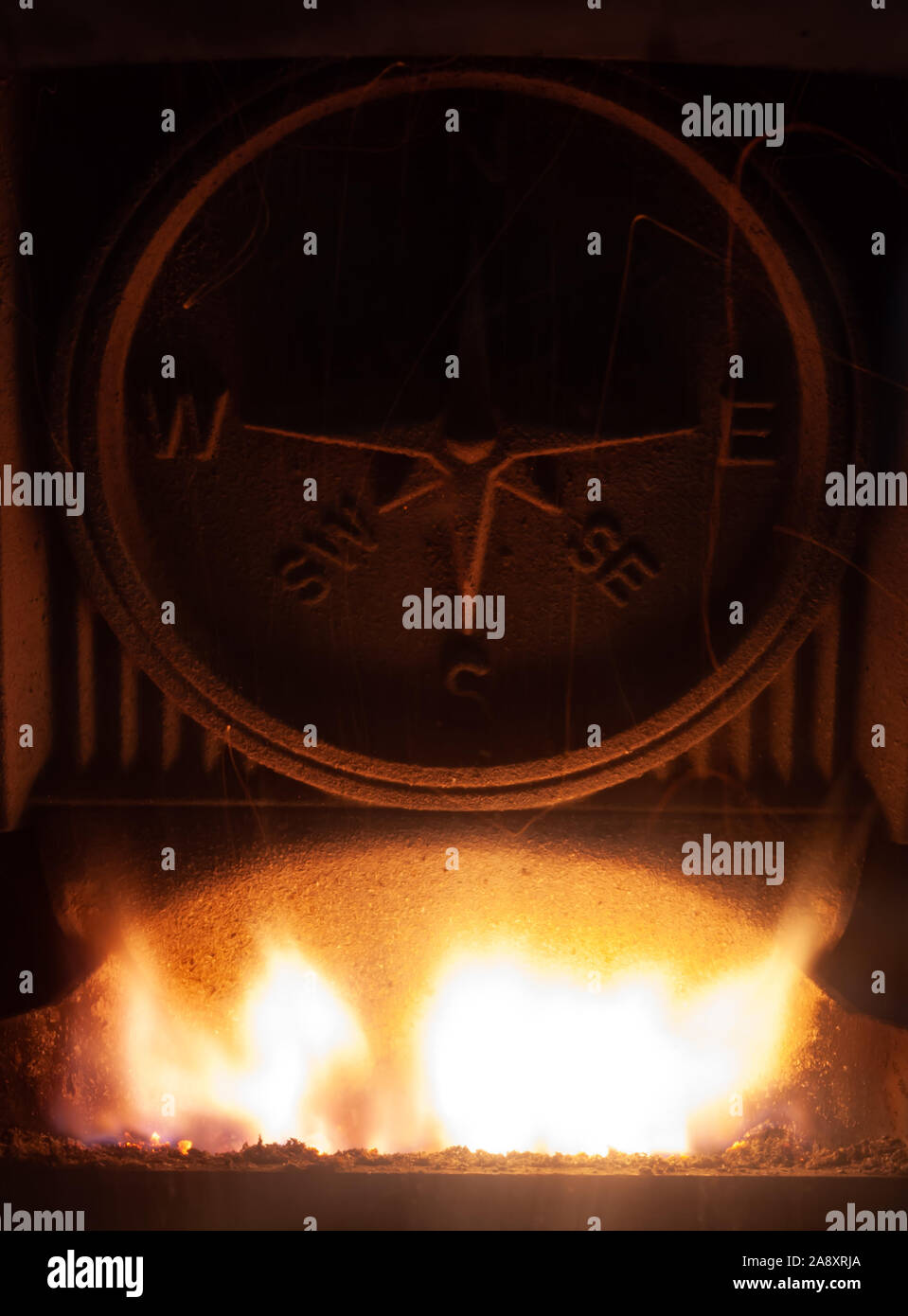 A Compass in a Fire Place with a Roaring Fire Stock Photo