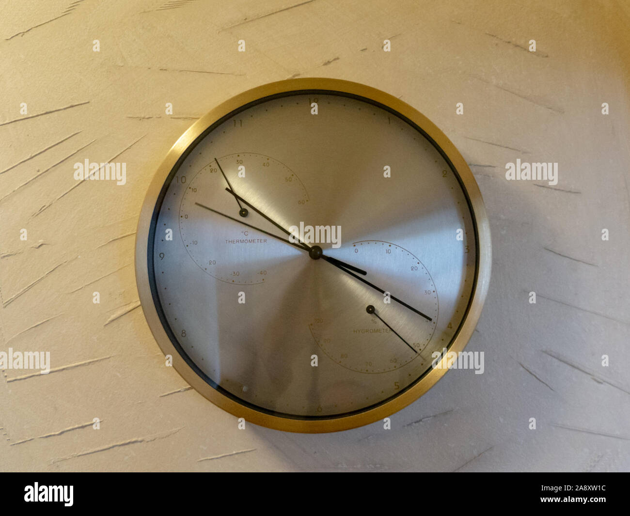 Round metal clock on white wall Stock Photo