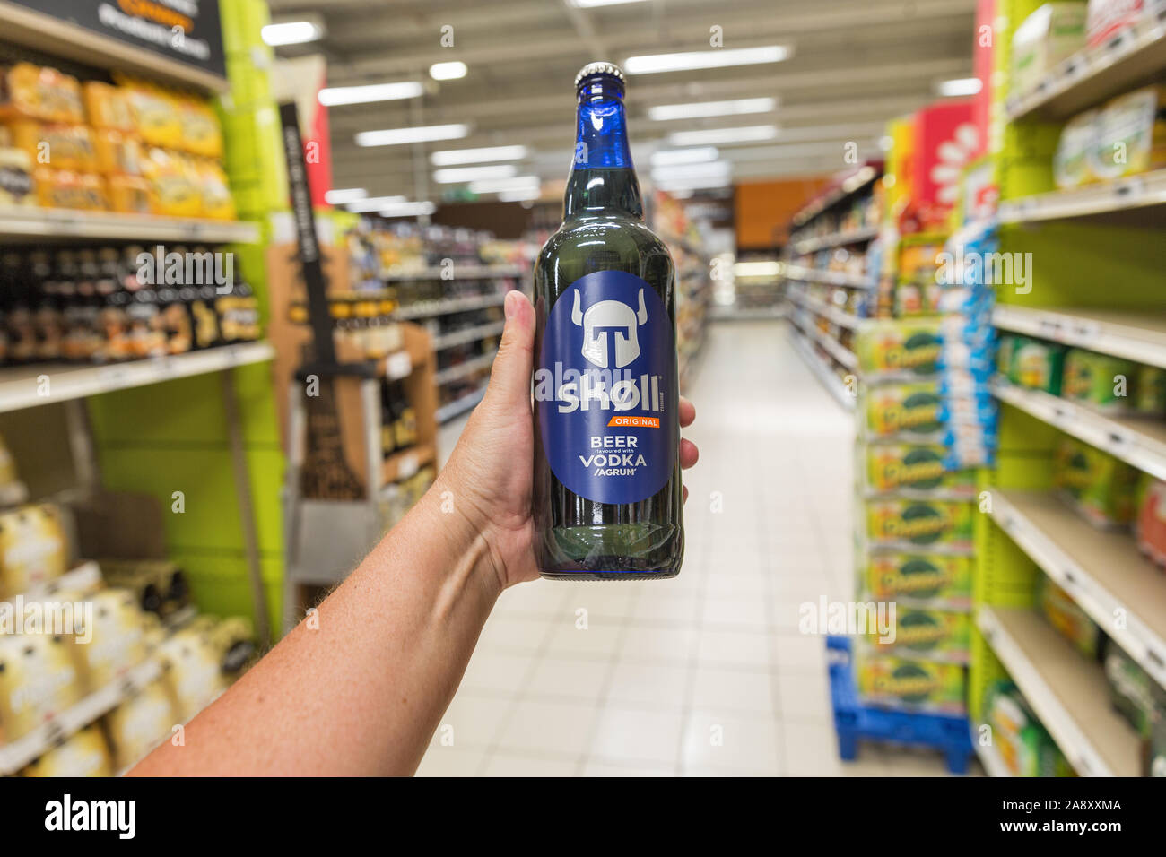 ALERIA, CORSICA, FRANCE - JULY 17, 2019: White man's hand holds a Skoll beer with vodka in E.Leclerc supermarket. Corsica is located southeast of the Stock Photo