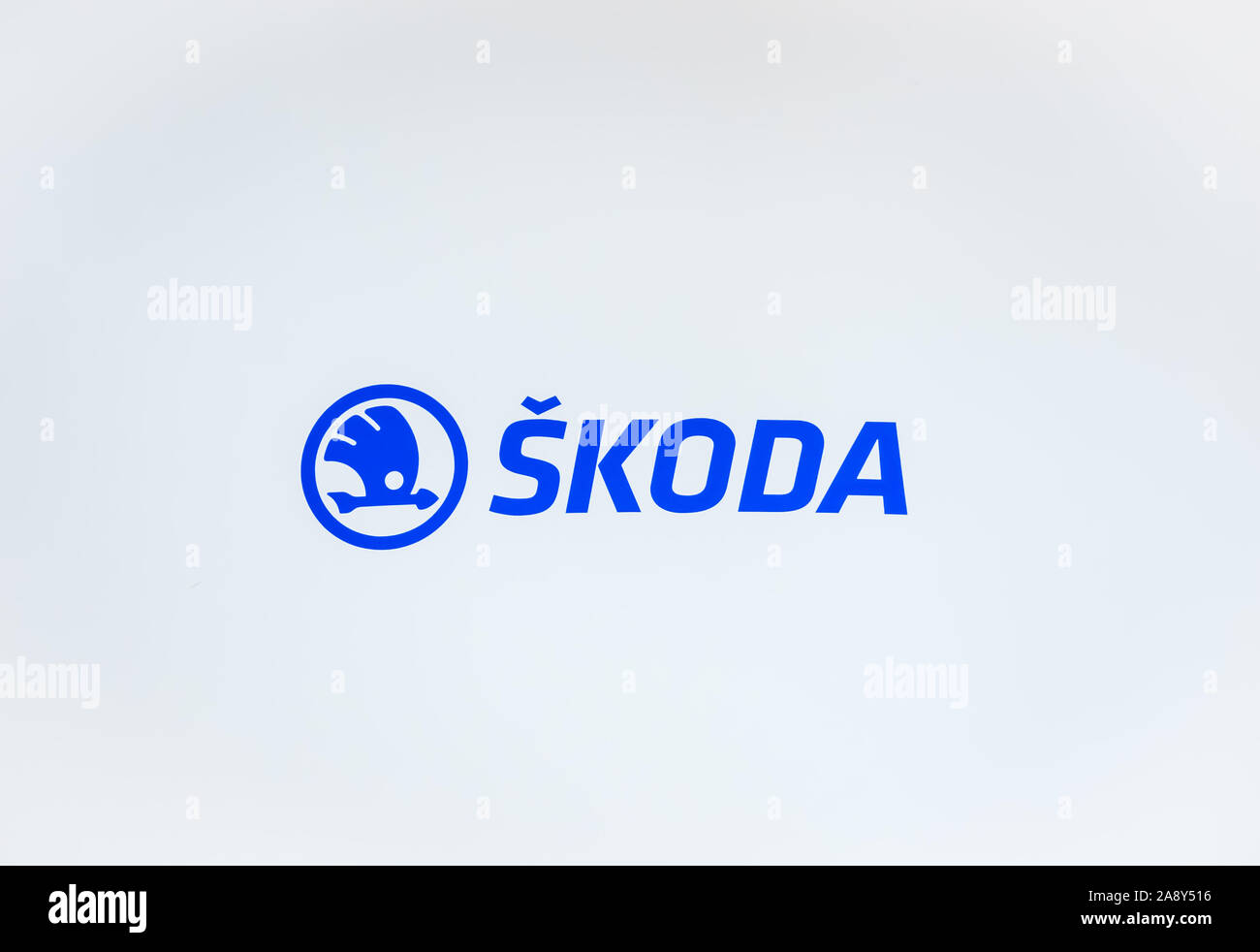 Plzen, Czech Republic - Oct 28, 2019: The original blue logo of Skoda photographed with a white wall background. Skoda is car manufacturer from Czechia. The company produces busses or turbines. Stock Photo