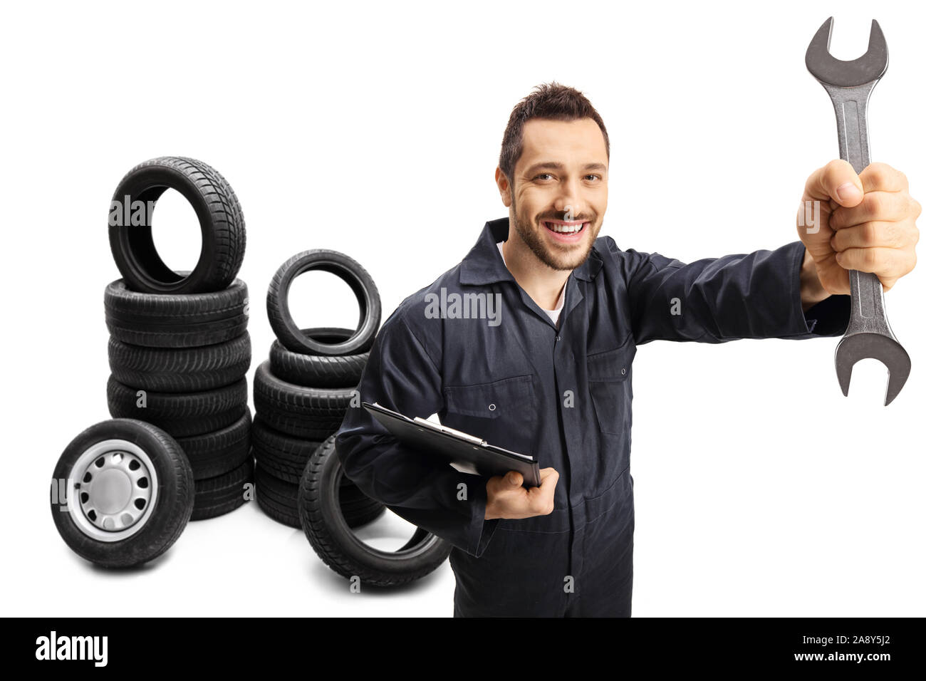 Auto mechanic holding a wrench with car tires in the back isolated on white background Stock Photo