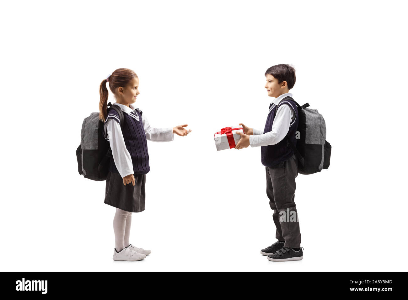 Full length profile shot of a schoolboy giving apresent to a schoolgirl isolated on white background Stock Photo