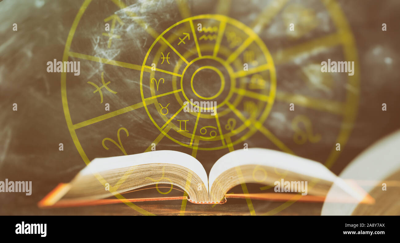 Astrology and horoscopes concept. Open book and astrological zodiac signs wheel, abstract background. Stock Photo