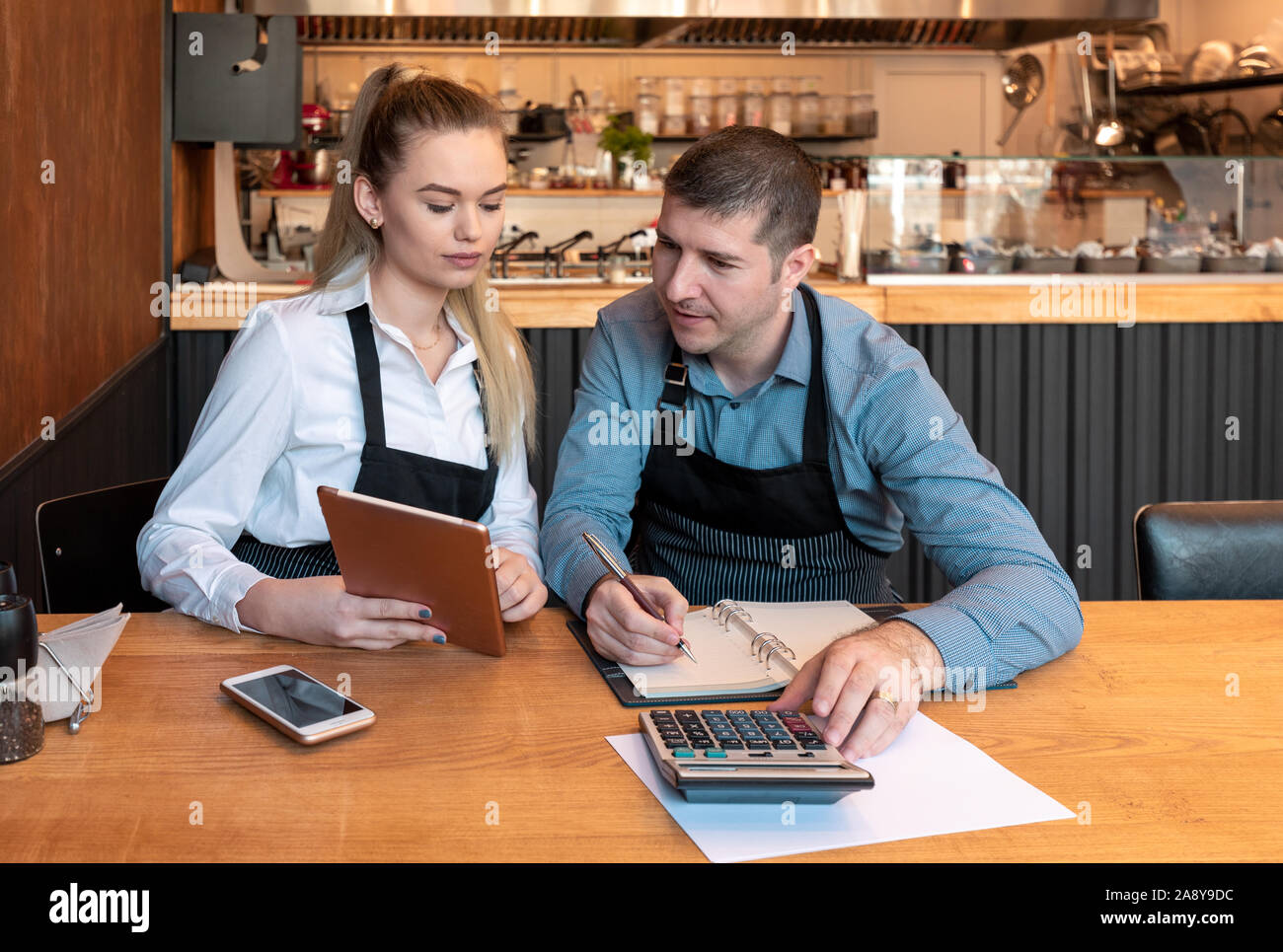 New small business owners counting revenue and expenses - Start-up entrepreneurs, woman and man, businessmen doing accounting with calculator and tabl Stock Photo