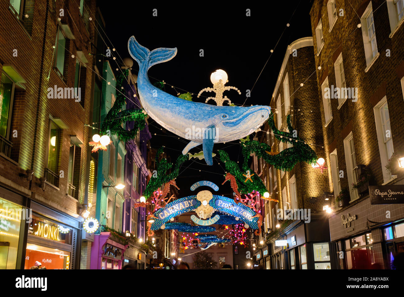 2019 Carnaby Street theme: One Ocean Sealife Christmas lights decoration made from recycled material. Colourful display lit up in evening, with crowd Stock Photo