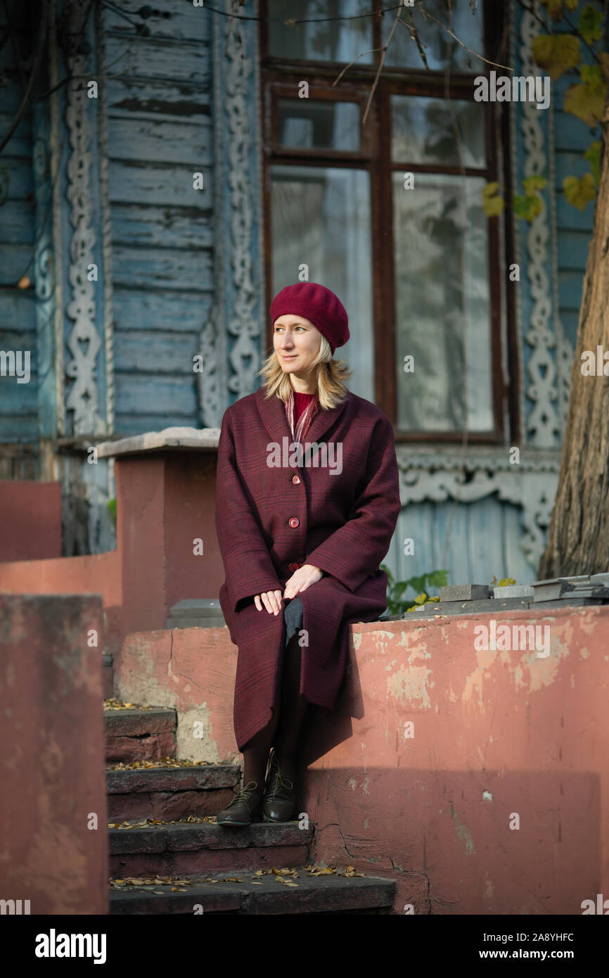Woman in a coat sitting on the porch of an old wooden house Stock Photo ...