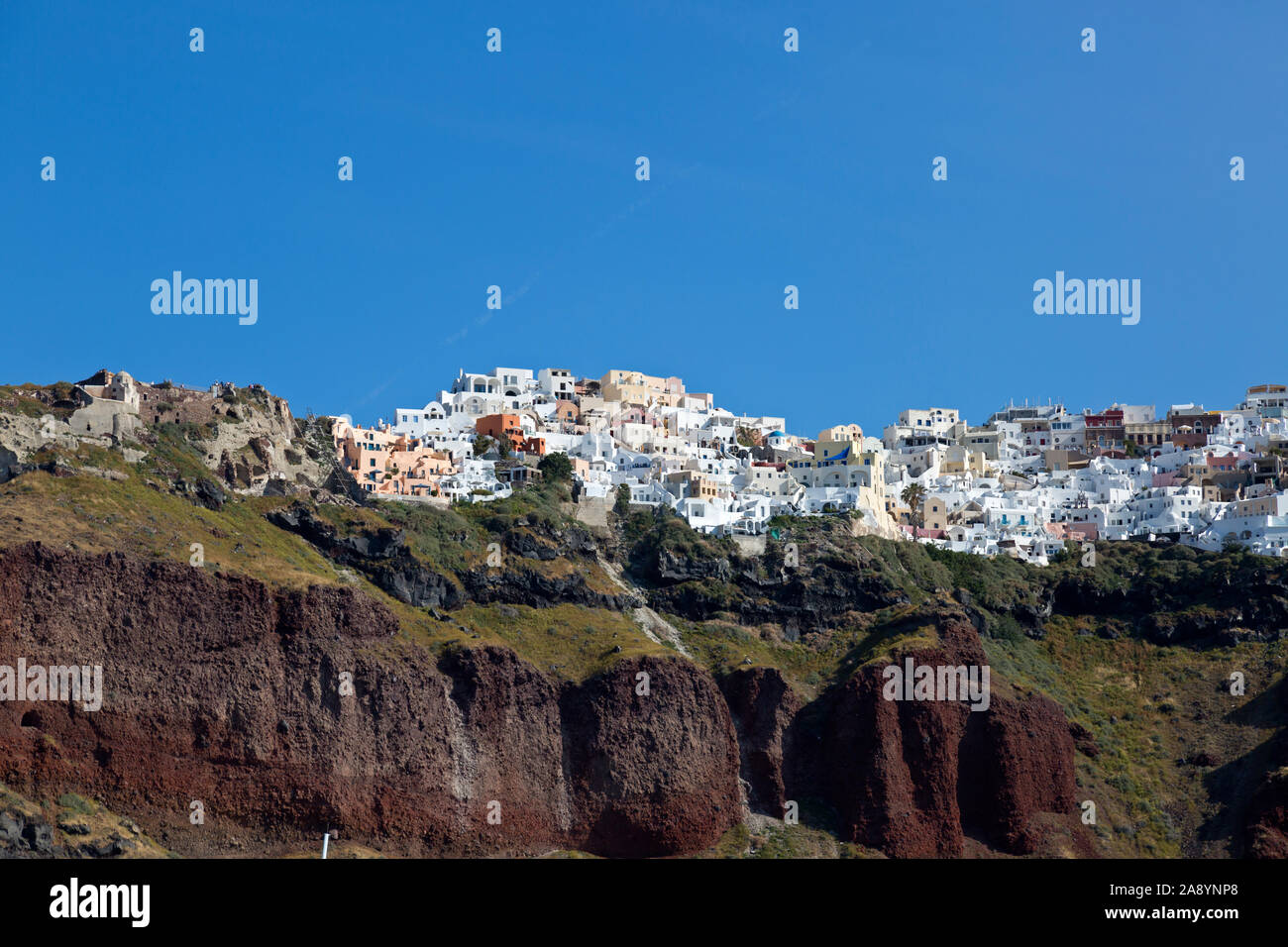 As viewed from below. On a sunny morning, a whitewashed town atop a hill on the popular island of Santorini. In the Cyclades of the Greek islands. Stock Photo