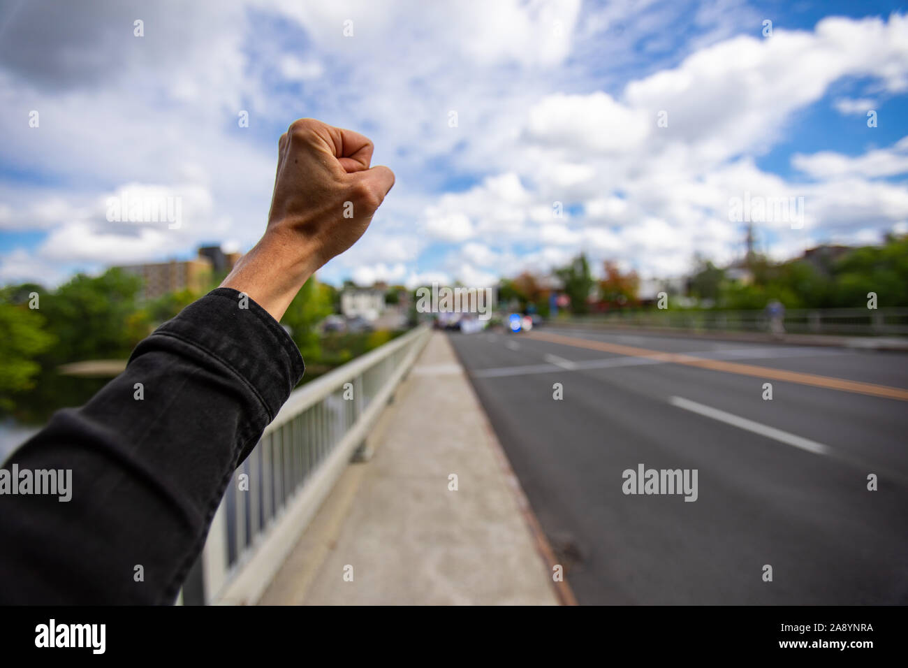 First person perspective and Selective focus on man fist raised during an ecological protest. Crowd of people walking against climate change  Stock Photo