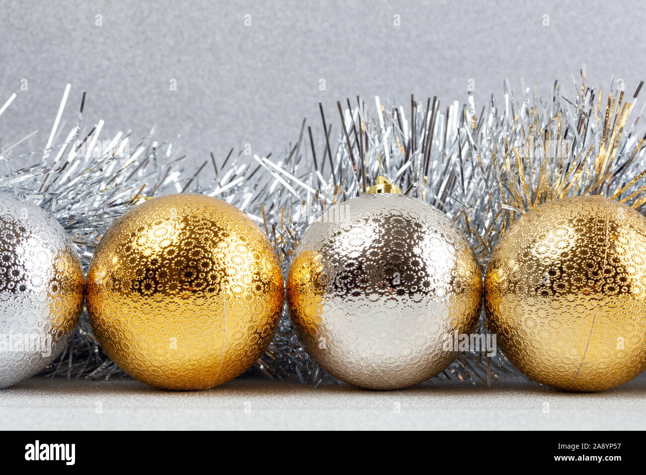 Row of Christmas baubles with silver tinsel on glittery background - closeup Stock Photo