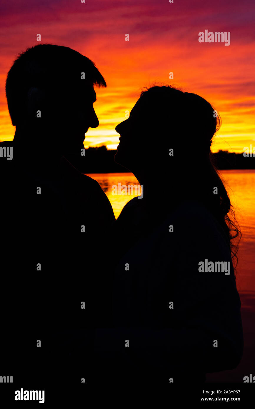 Silhouette of a couple in front of a lake sunset Stock Photo - Alamy
