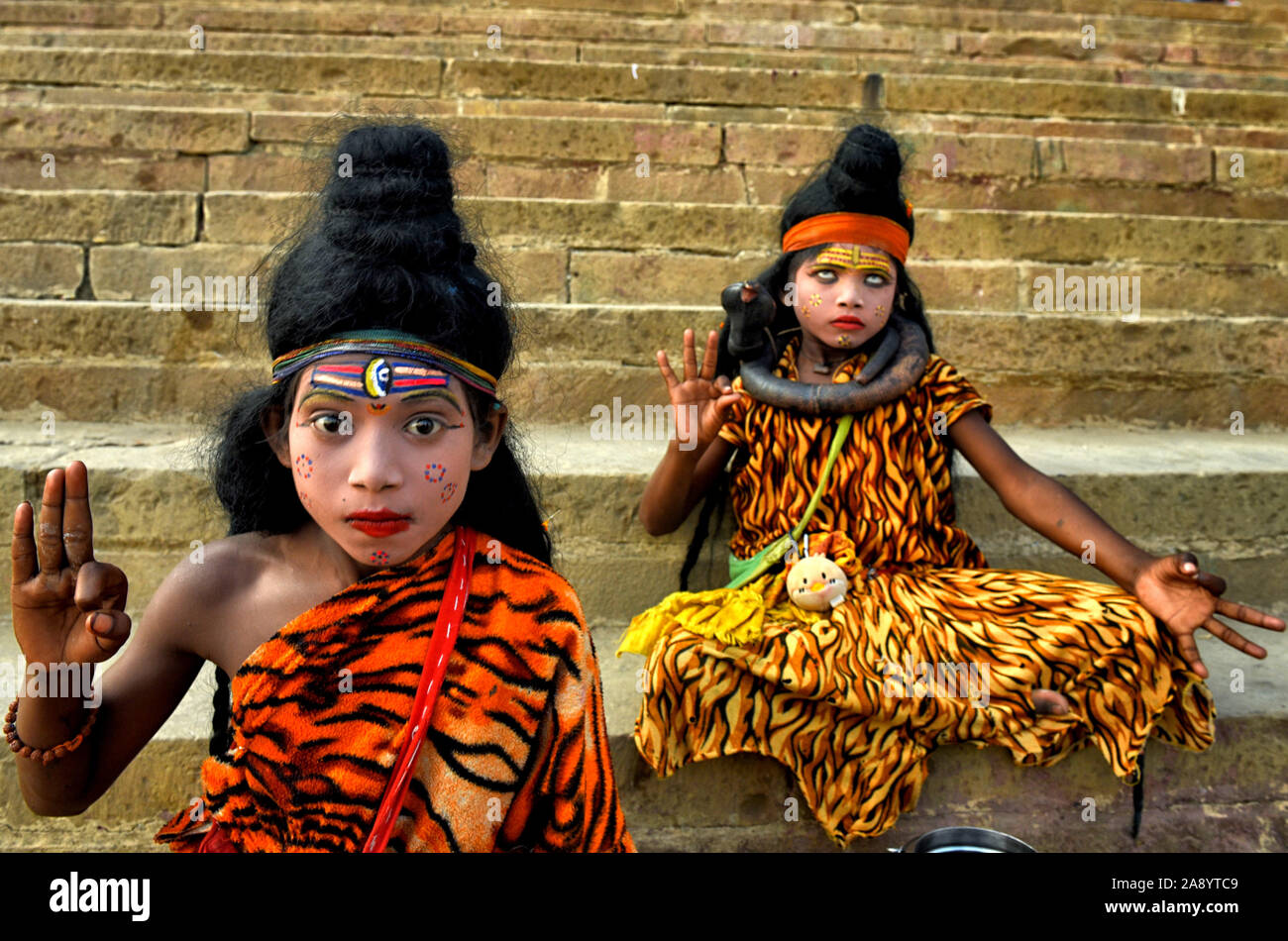 Two children dressed as Lord Shiva collecting Offerings from Devotees during the festival.Dev deepavali / Diwali is the biggest festival of light celebration in Kartik Poornima (Mid-Autumn) where devotees decorate the river bank with millions of Lamps as part of the festival. Stock Photo