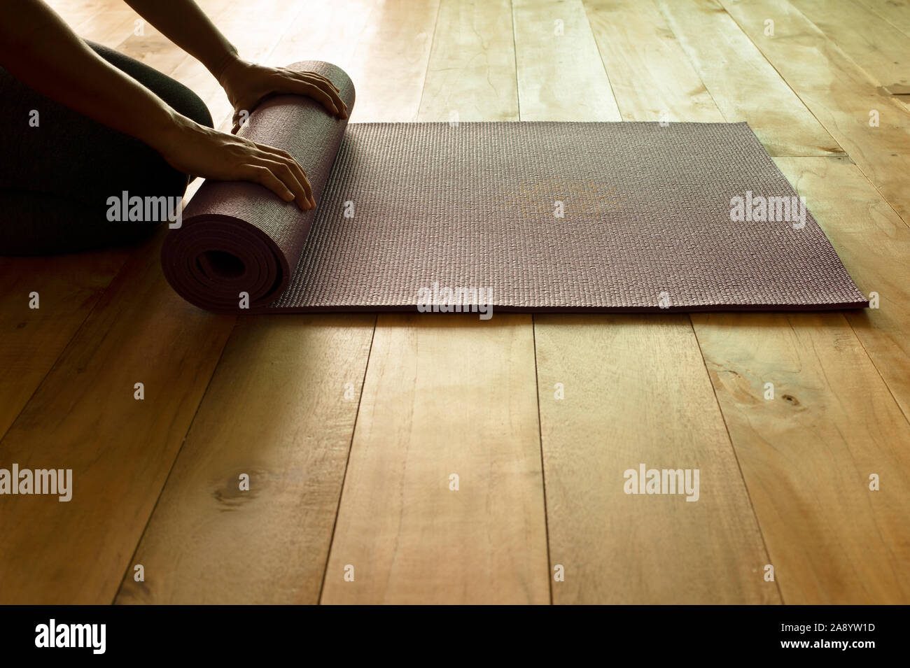 Silhouette Hands Of Adult Woman Folding Yoga Or Fitness Mat After