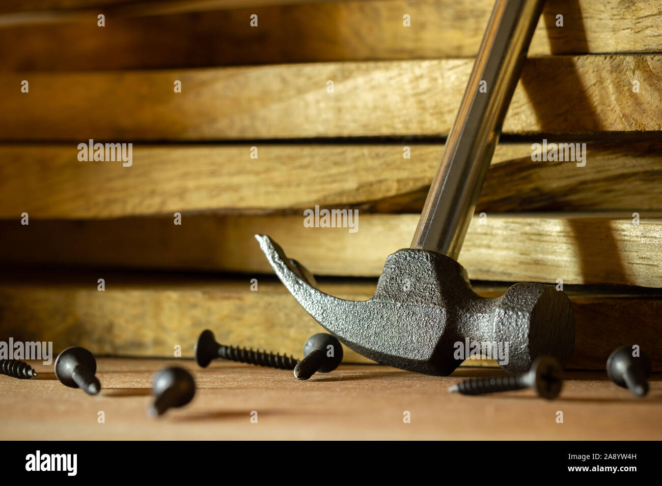 Hammer and screw on lumber in lighting and shadow of the sunshine in morning. The concept of woodcraft or carpentry. Stock Photo