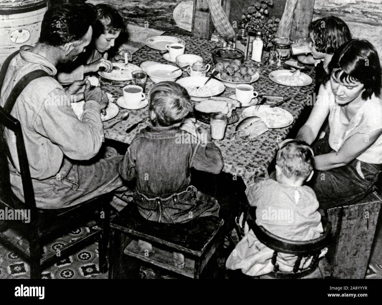 Family eating meal of hominy grits, mush, molasses, cabbages, potatoes, and rice ca. 1920 Stock Photo