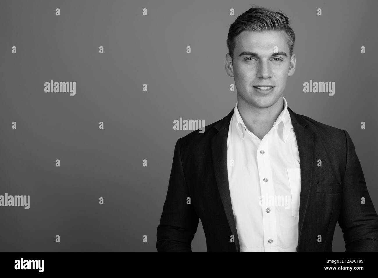 Face of young handsome businessman wearing suit in black and white ...