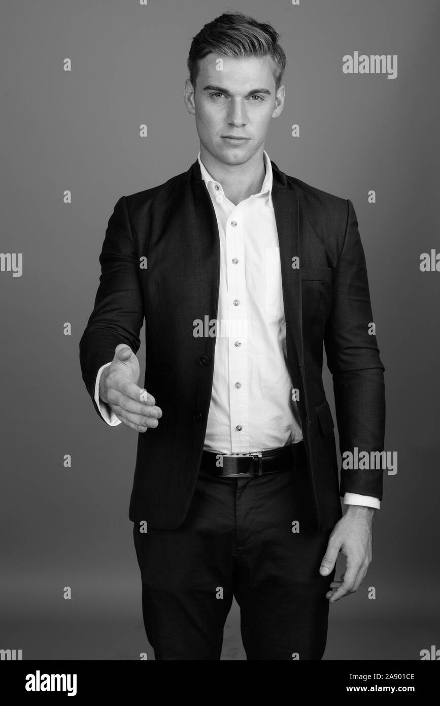 Portrait of young handsome businessman wearing suit in black and white ...