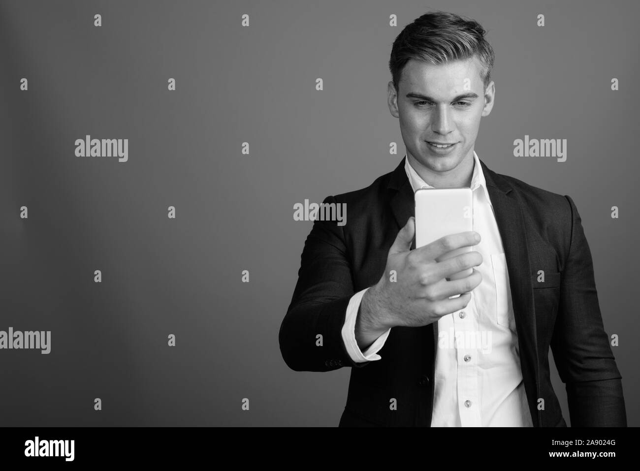 Portrait of young handsome businessman wearing suit in black and white ...