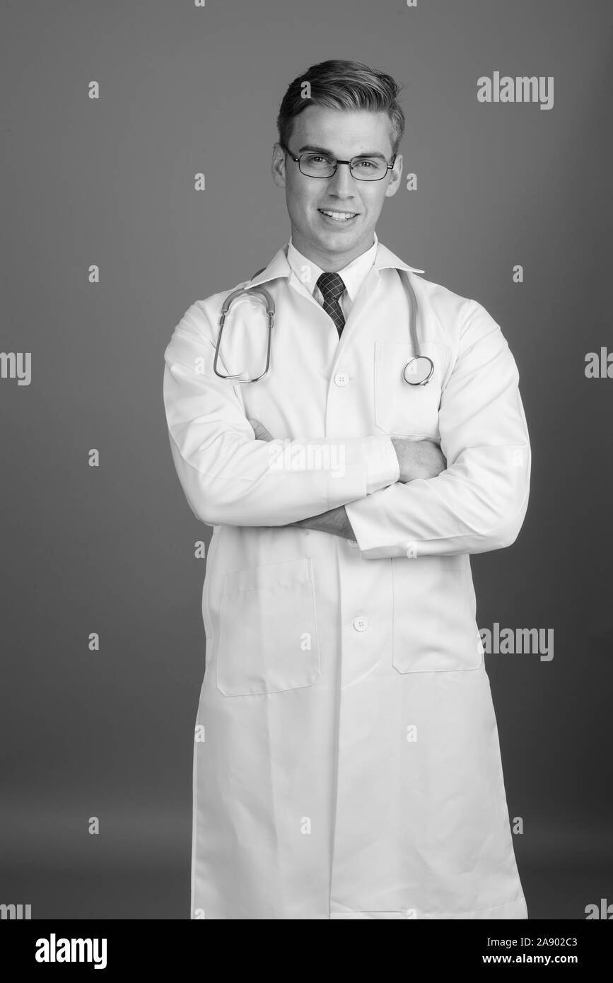 Portrait of young handsome man doctor with eyeglasses in black and ...