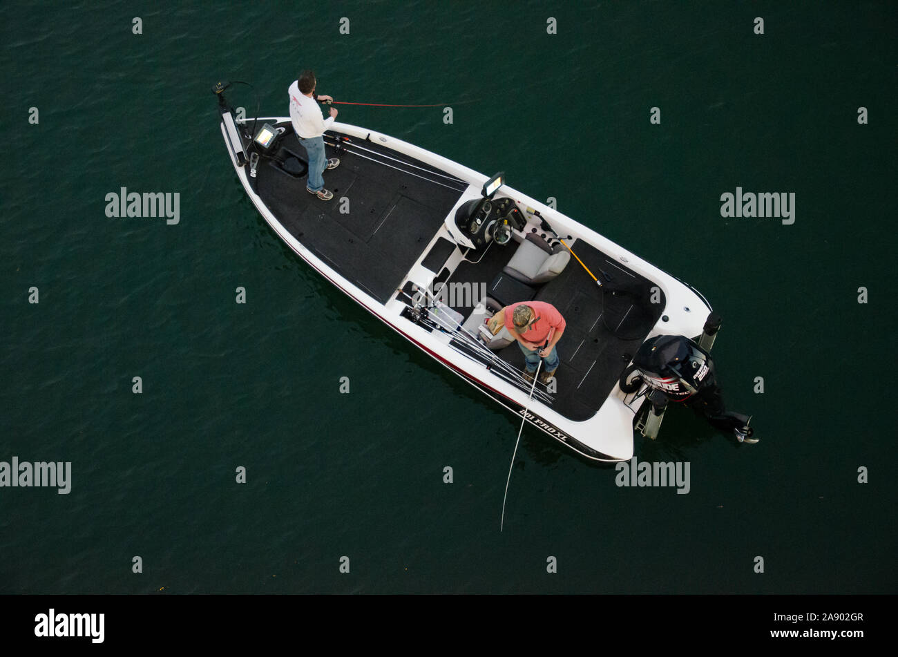 Two men fishing off a boat on the Colorado River in Austin Texas Stock Photo
