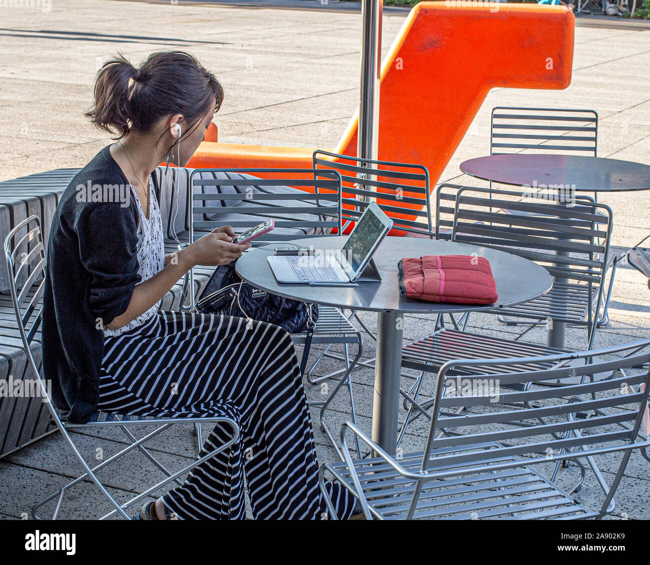 Woman working on her laptop at an outdoor table in Harvard Square, Cambridge, MA Stock Photo