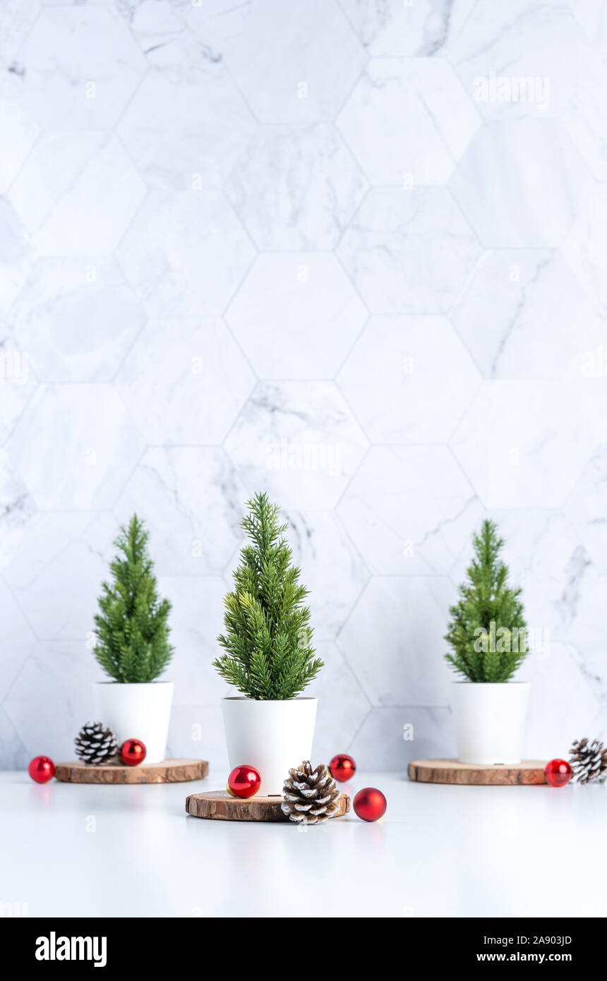 Three christmas tree with pine cone and decor xmas ball on white table and marble tile wall background.clean minimal simple style.holiday still life m Stock Photo