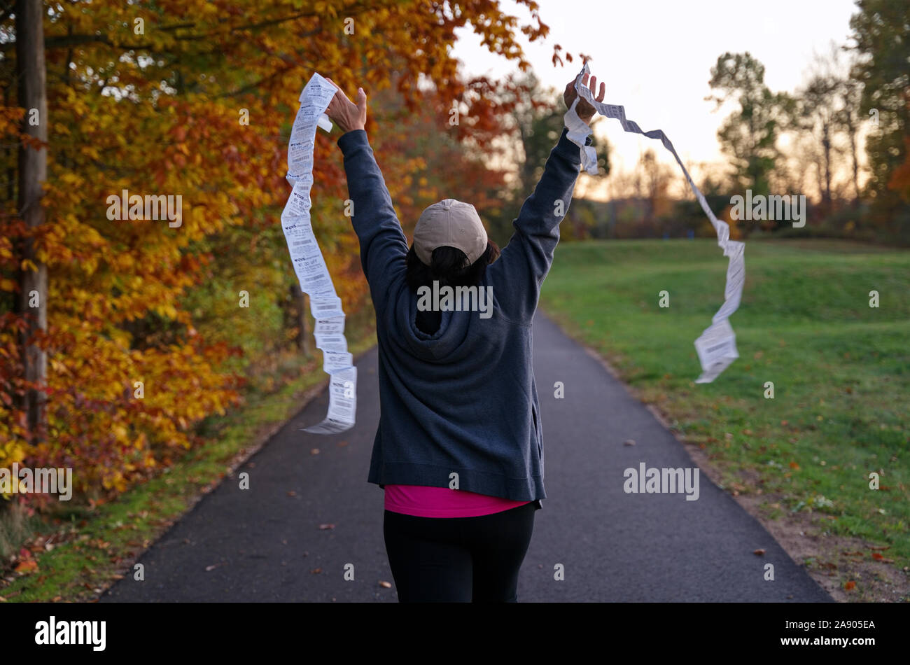 Middletown, CT USA. Oct 2019. Woman rushing from an autumn park waving discount coupons to be used at a local pharmacy store. Stock Photo