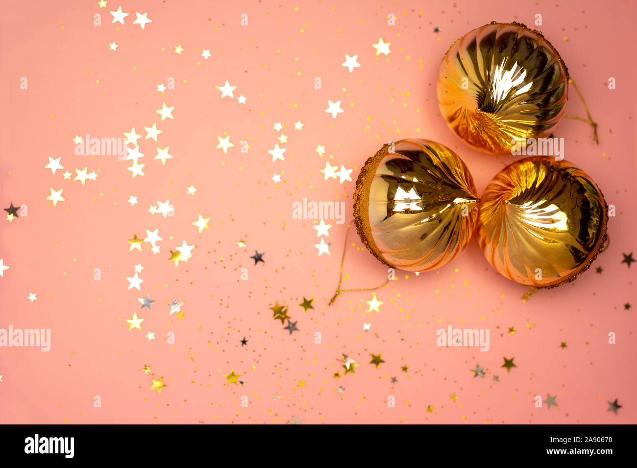 Scattered stars and Christmas tree balls on a coral color background, Christmas, New year decorations Stock Photo