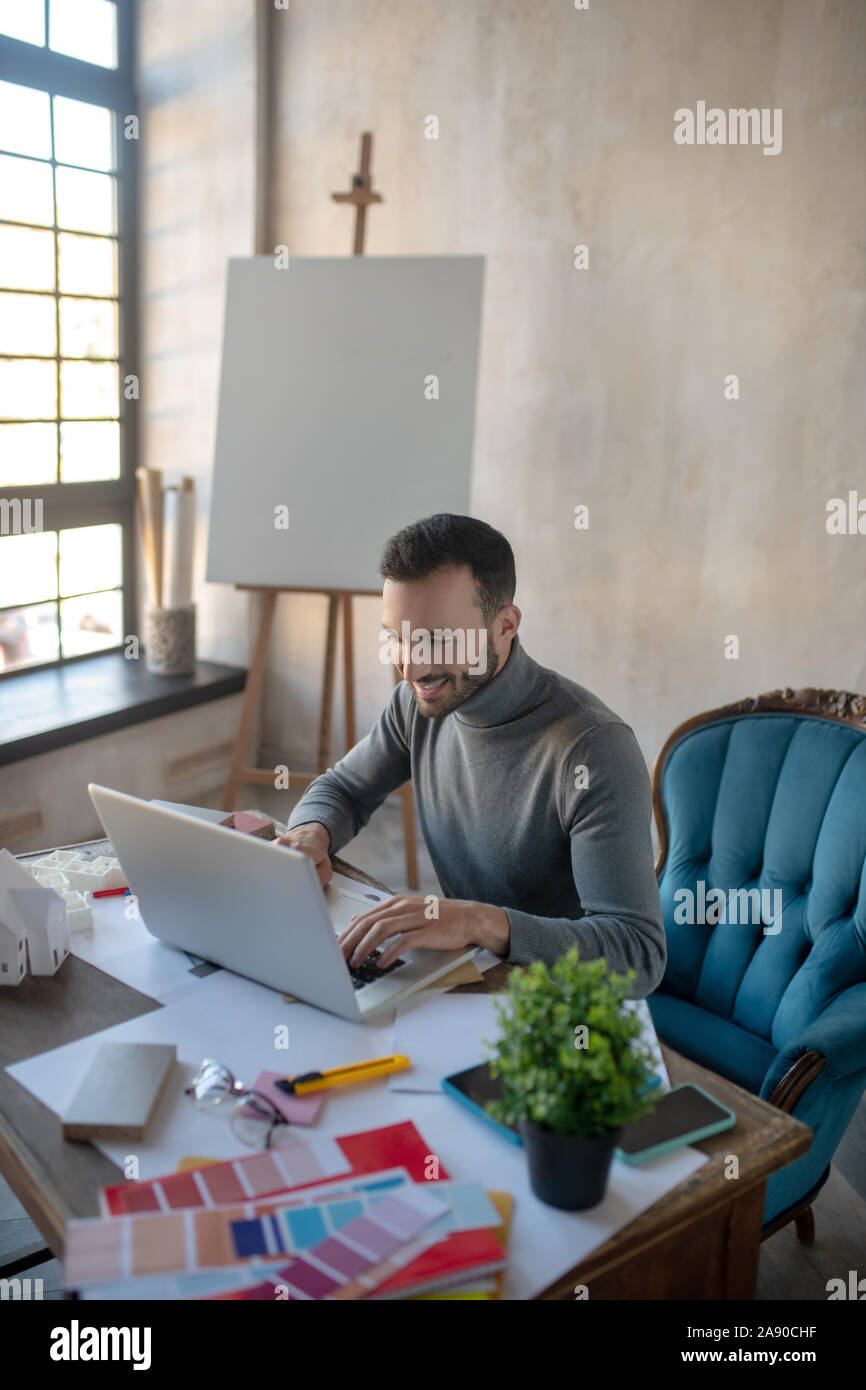Designer smiling while reading e-mail from colleague Stock Photo