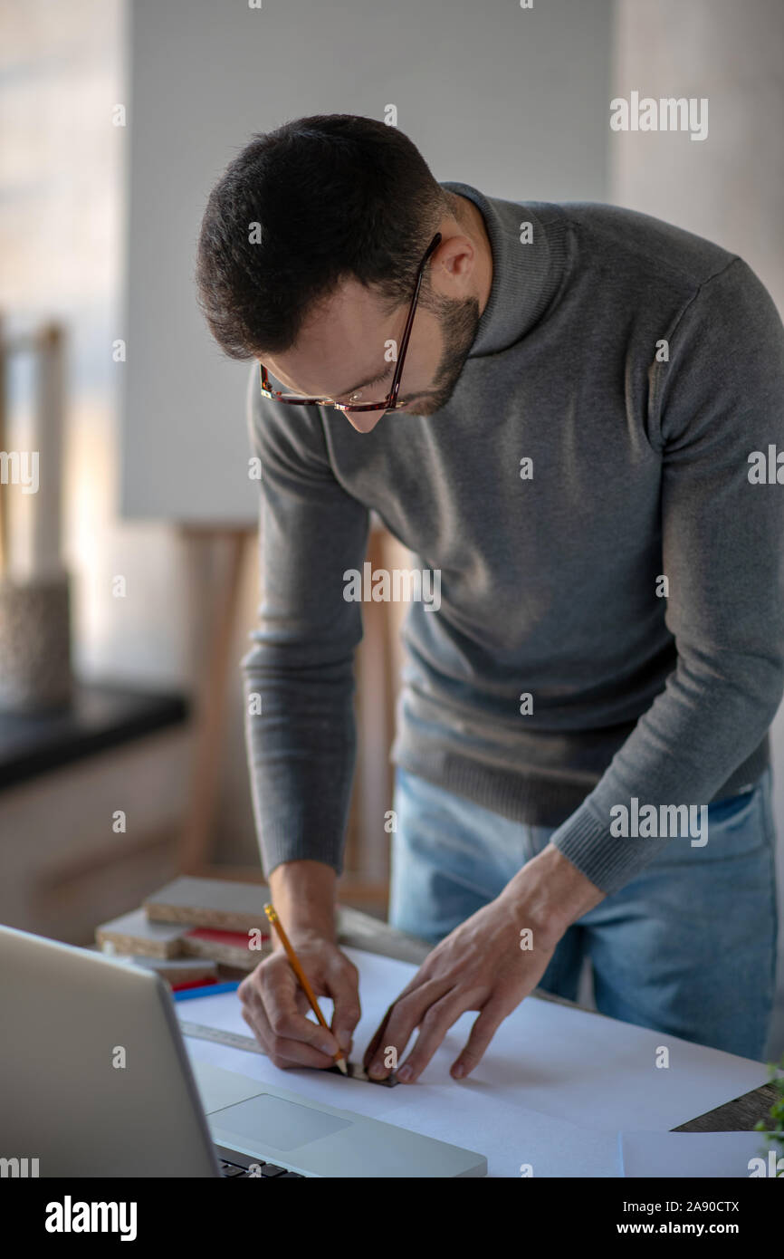 Interior designer wearing glasses feeling busy making sketches Stock Photo