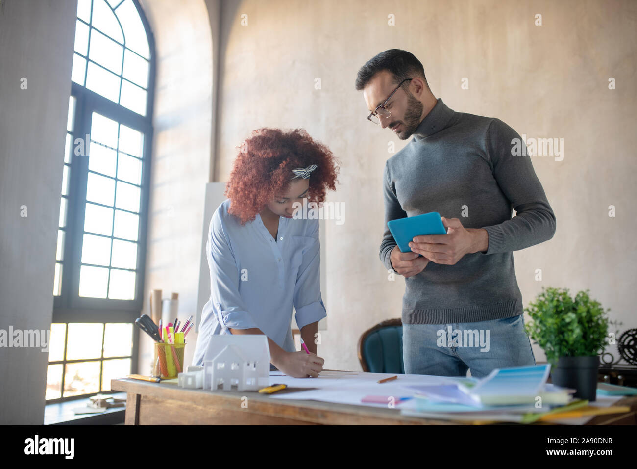 Bearded interior designer watching trainee making sketches Stock Photo