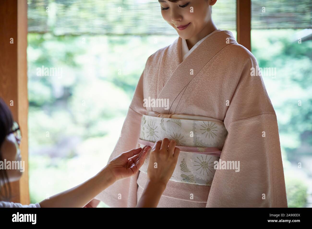 Young Japanese woman putting on traditional kimono Stock Photo - Alamy