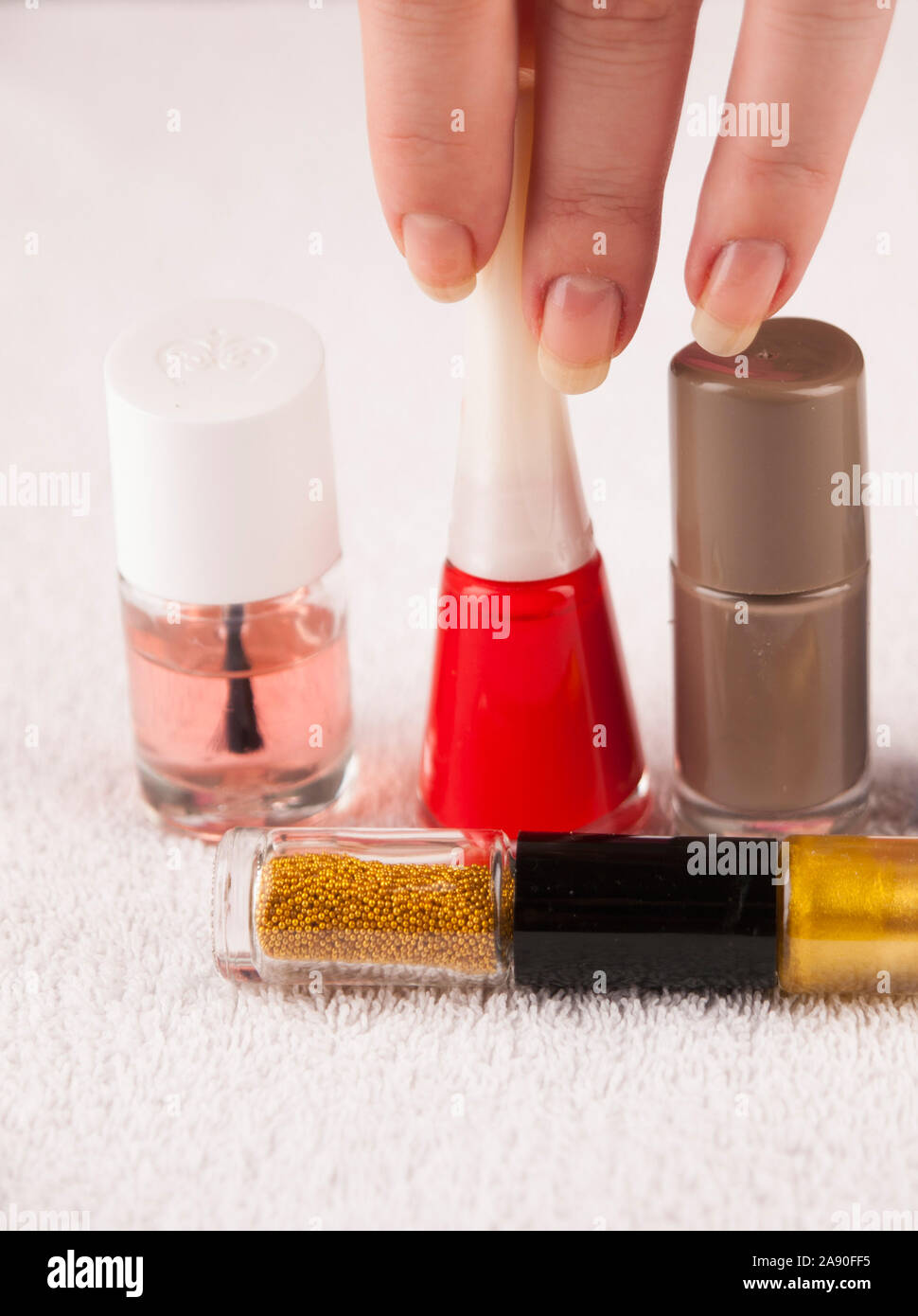 Detail of hand choosing  between various color of nail polishes Stock Photo