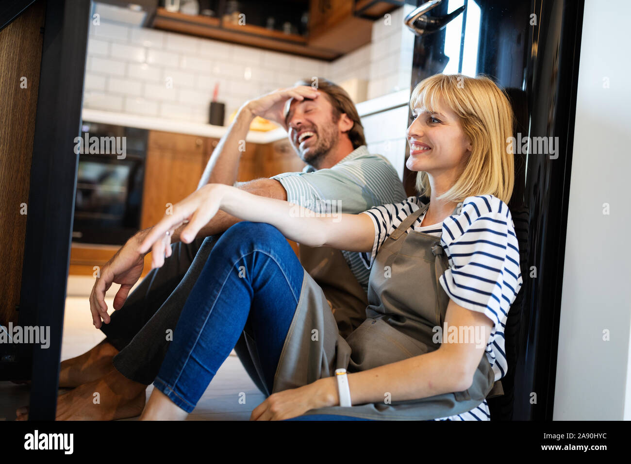 Young happy tired couple sitting on kitchen floor after cooking Stock Photo